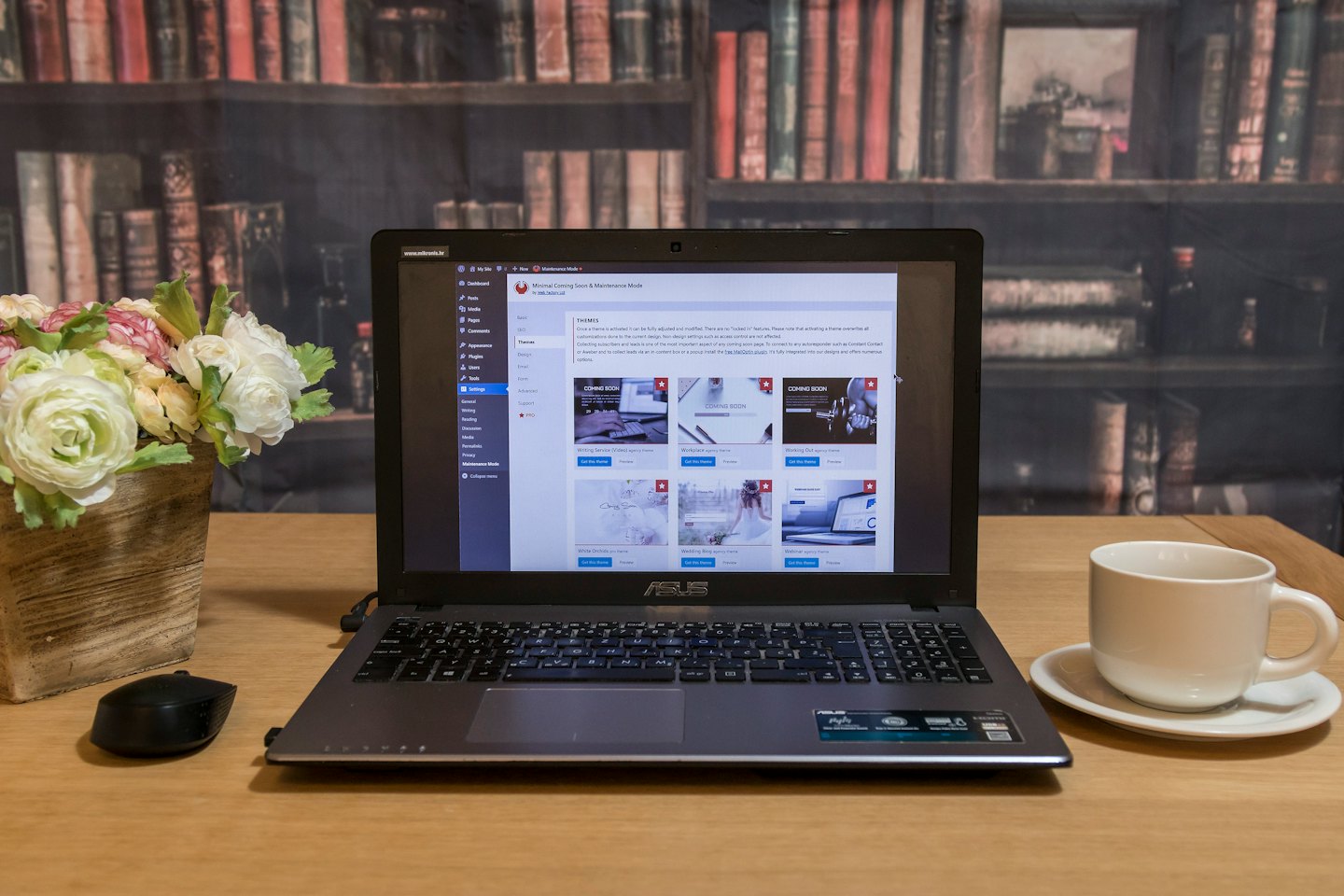 Ordinateur portable affichant une interface de backend de site web à côté de renoncules et d'une tasse de café.