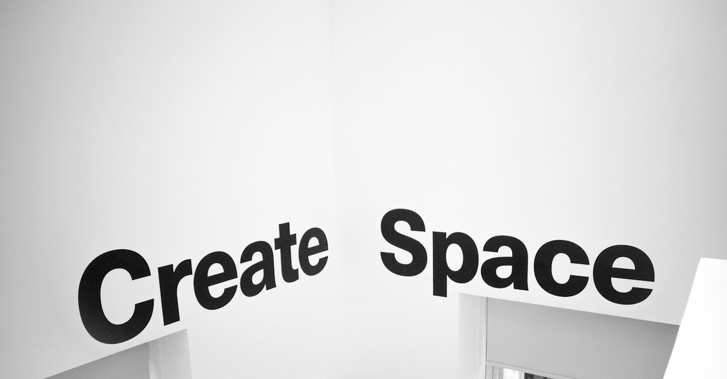 Texte noir "Create Space" sur un mur blanc.